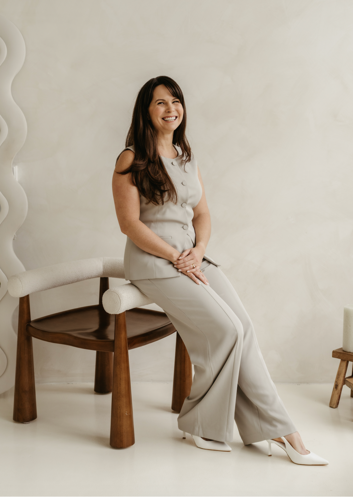 Woman sitting on a chair in a minimalistic room with a white wall.